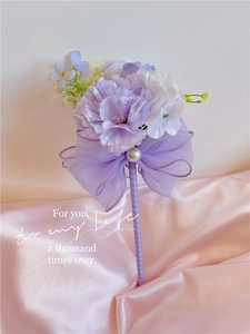 Detail of purple artificial flower pen with chiffon bow and pearl on pink satin fabric