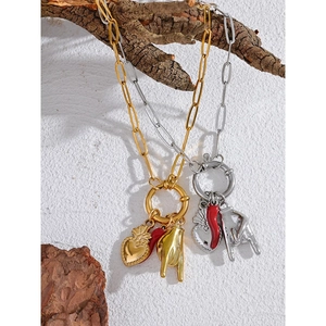 Detail of red horn and heart pendants on gold and silver chain hanging on a branch