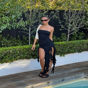 Detail of black strapless dress featuring asymmetric ruffled hem and slim fit design