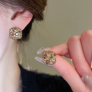 Close-up of gold-plated square stud earrings with brown crystals and micro-pavé diamonds