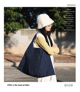 Detailed view of large dark blue pleated nylon tote bag worn by a model in outdoor setting