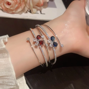 Dettaglio di bracciale aperto a tre strati con pietre di zircone a cuore e design a farfalla