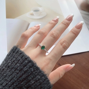 Macro detail of emerald-cut zircon ring with silver band worn on hand over wood surface
