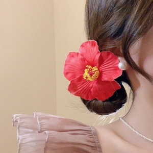 Detailed view of a realistic red hibiscus flower hair clip with yellow stamen on elegant bun