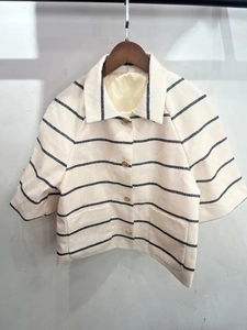 Detail of striped cream and navy knit cardigan with elegant gold round buttons