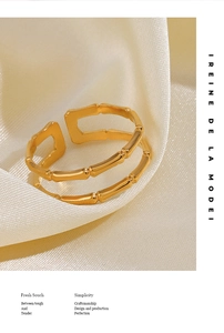 Détail d'une bague double couche dorée au motif bambou sur tissu en satin blanc