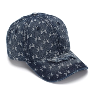 Close-up of distressed denim baseball cap with white butterfly patterns and frayed brim