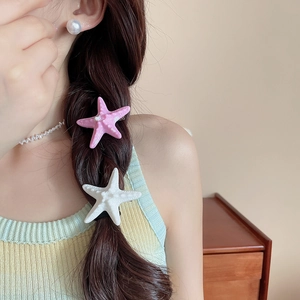 Detail of pink and white starfish hair clips styled on a woman's braided hair