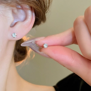 Close-up of minimalist silver zircon stud earrings featuring a classic four-prong setting
