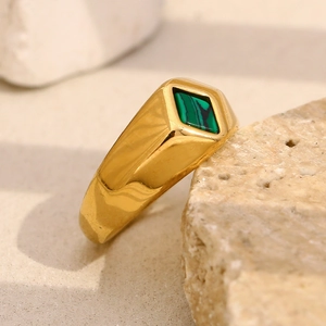 Macro shot of 18K gold geometric ring with green malachite inlay on natural stone