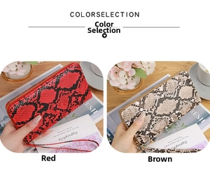 Detail of snake skin texture clutch bags in red and brown colors on wooden background