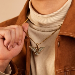Close-up of golden punk double-headed eagle pendant on male model wearing beige turtleneck