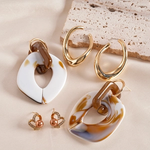 Detail of diverse earrings set featuring marble acrylic, gold hoops and pearl hearts