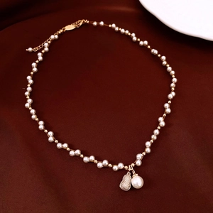 Detailed close-up of a French pearl necklace with a pavé zircon gourd pendant on red velvet