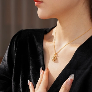 Détail d'un collier floral doré avec perles porté par un mannequin sur du velours