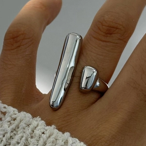Detailed close-up of a silver geometric open ring with polished cylindrical accents