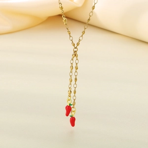 Detail of gold beaded chain necklace with two vibrant red enamel chili pepper pendants