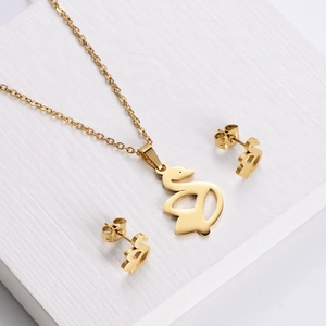 Parure de bijoux cygne doré avec collier et boucles d'oreilles sur pierre texturée