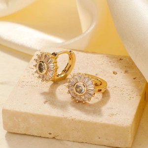 Golden flower earrings with rectangular zircons on a stone and satin background