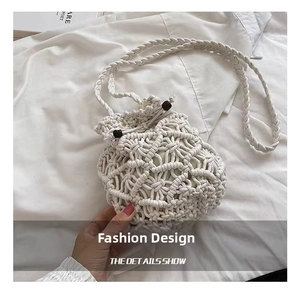 Close-up of white macrame woven bucket bag with drawstring and dark wooden bead accents