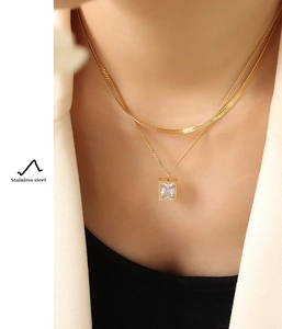 Detail of gold double-layered stainless steel necklace with square zircon pendant