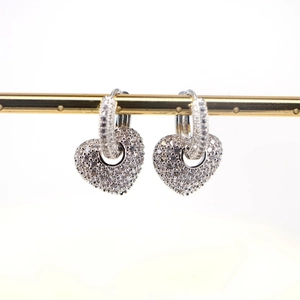 Close-up of silver heart-shaped dangle earrings featuring micro-pave cubic zirconia crystals