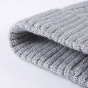 Women's grey cable knit beanie hat showing thick ribbed texture and folded brim detail