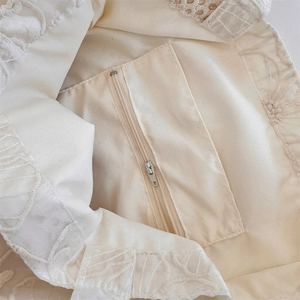 Macro view of interior zipper pocket and floral embroidery on cream canvas tote bag