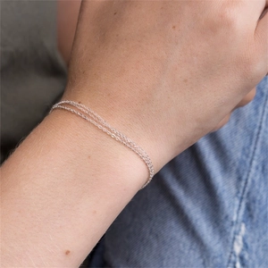 Detail shot of triple-layer silver stainless steel chain bracelet on a model wrist