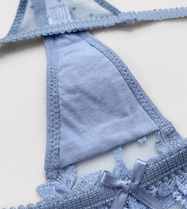 Detailed macro shot of light blue lace embroidery with delicate bow and cotton crotch