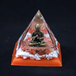 Macro detail of Orgone energy pyramid featuring a bronze Buddha statue and crystals