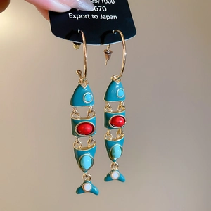 Close-up of a vintage peacock blue enamel fish tassel earring with jointed gold frame