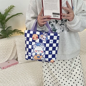 Detail of blue checkerboard canvas tote featuring cute cartoon bear and purple handles