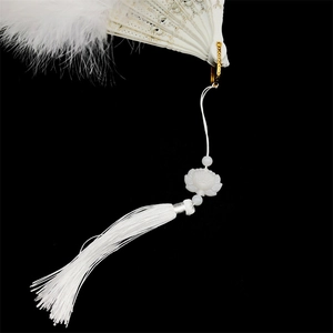 Elegant white feather fan with golden hollowed ribs and long white tassel on black background