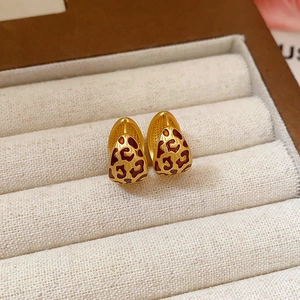 Golden teardrop leopard print earrings with red enamel detail on a jewelry box display