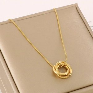 Detail of interlocking gold triple-ring pendant on a sleek snake chain over a jewelry box