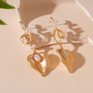 Detail of baroque pearl gold vine earrings with leaf shape and textured metal finish