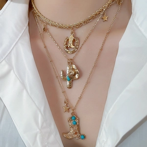 Detail of layered gold cowboy necklace with turquoise boot and cactus pendants