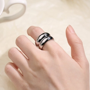 Close-up of wide polished silver stainless steel ring worn on index finger in minimalist style