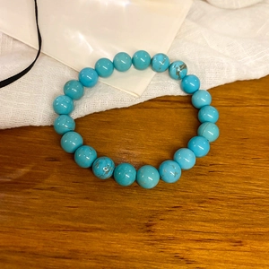 Close-up of artificial turquoise beaded stretch bracelet with natural veined textures