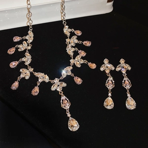 Detailed shot of pink teardrop crystal necklace and earrings set on black velvet display
