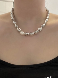 Detail of 14K gold plated necklace with irregular metal beads and a single white pearl
