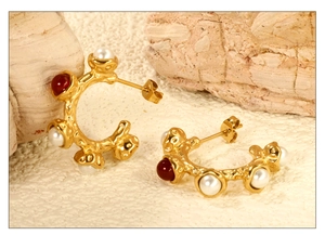 Detail view of gold-plated wrinkled earrings with white pearl and red gemstone inlay