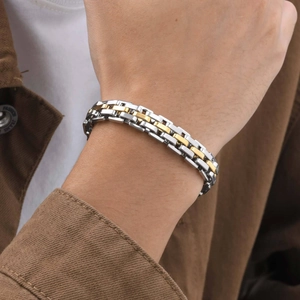 Macro detail of men's stainless steel watchband-style bracelet in silver and gold tone