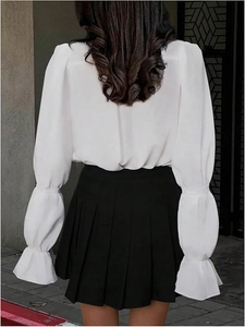 Rear view of white chiffon shirt with lantern sleeves and ruffled cuffs with black skirt