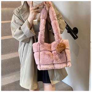 Detail of pink faux fur woven handbag with cute brown bear charm on soft plush texture