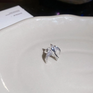 Macro shot of silver swallow ring with sparkling zircon inlays on a ceramic tray