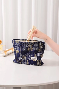 Detailed embroidery view of deep blue floral makeup bag with top zipper opening