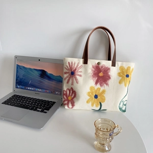 Detail of floral canvas tote bag featuring brown leather handles and magnetic button