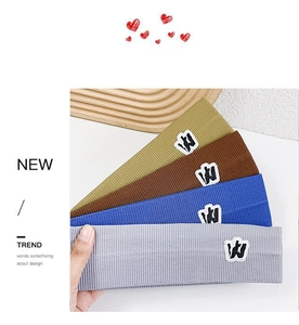 Detail of four colorful ribbed knit headbands with letter W embroidery in a stack